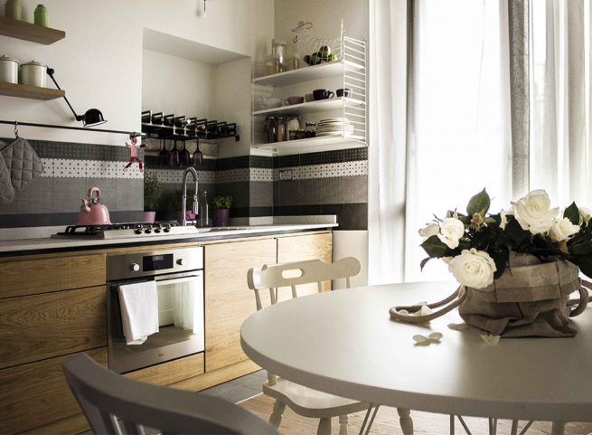 Cucina moderna in legno con tavolo bianco e centrotavola di rose bianche.